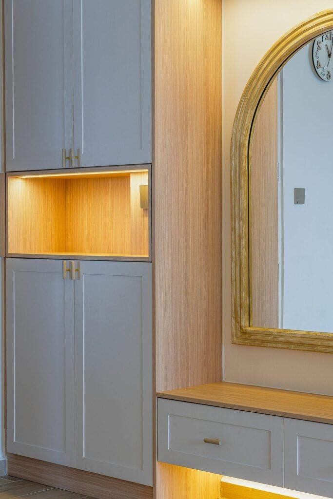 Shoe cabinet with lit open shelf and brass-framed arched mirror