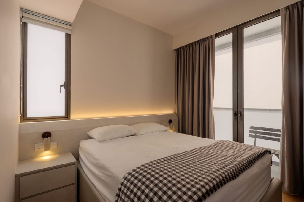 Bedroom with a lit headboard ledge and full-height curtains