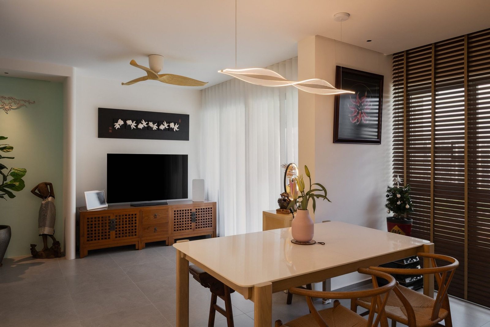Open dining and living area with a pale timber table and carved TV console